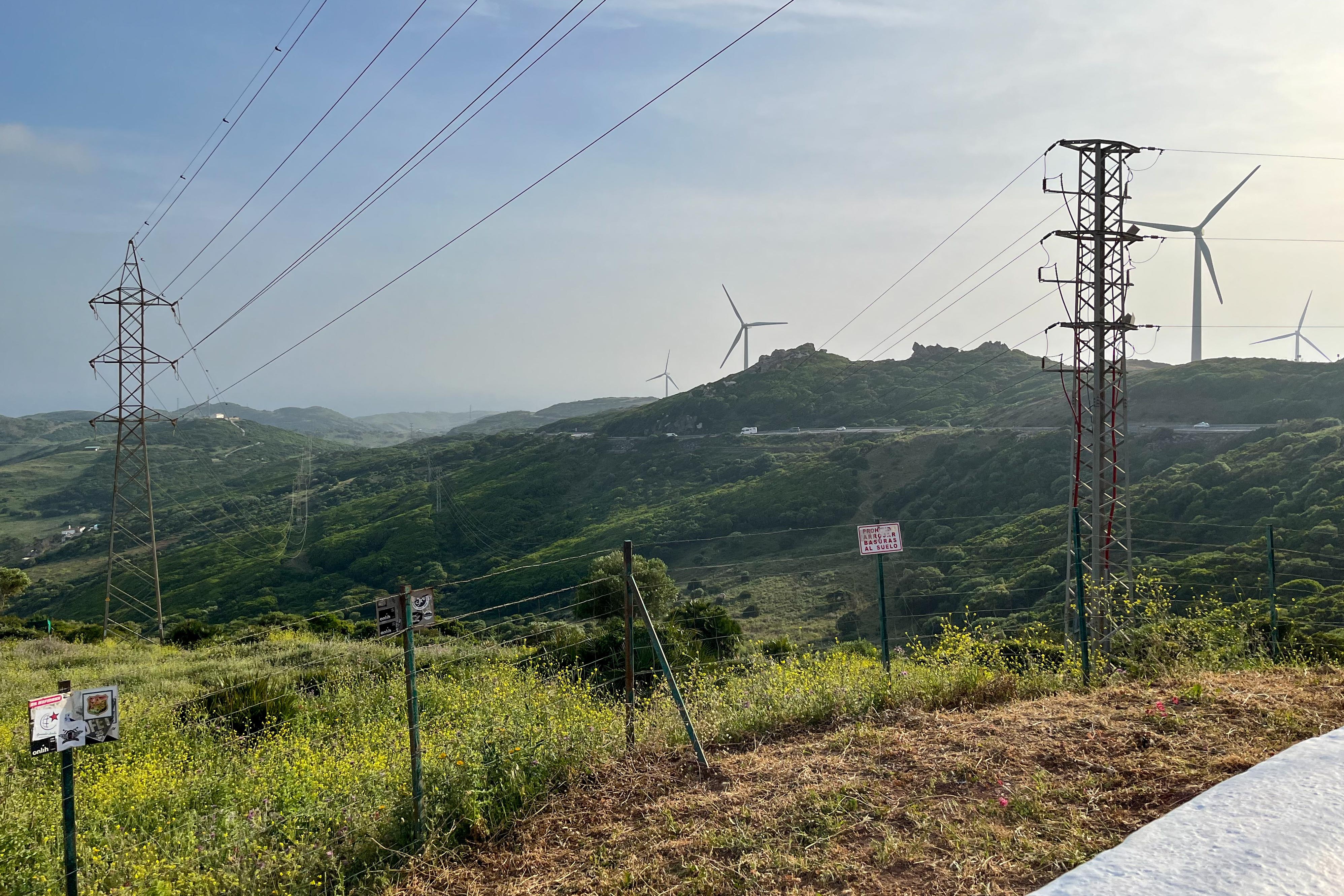 Eine Stromtrasse, im Hintergrund Windräder