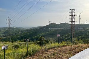 Eine Stromtrasse, im Hintergrund Windräder